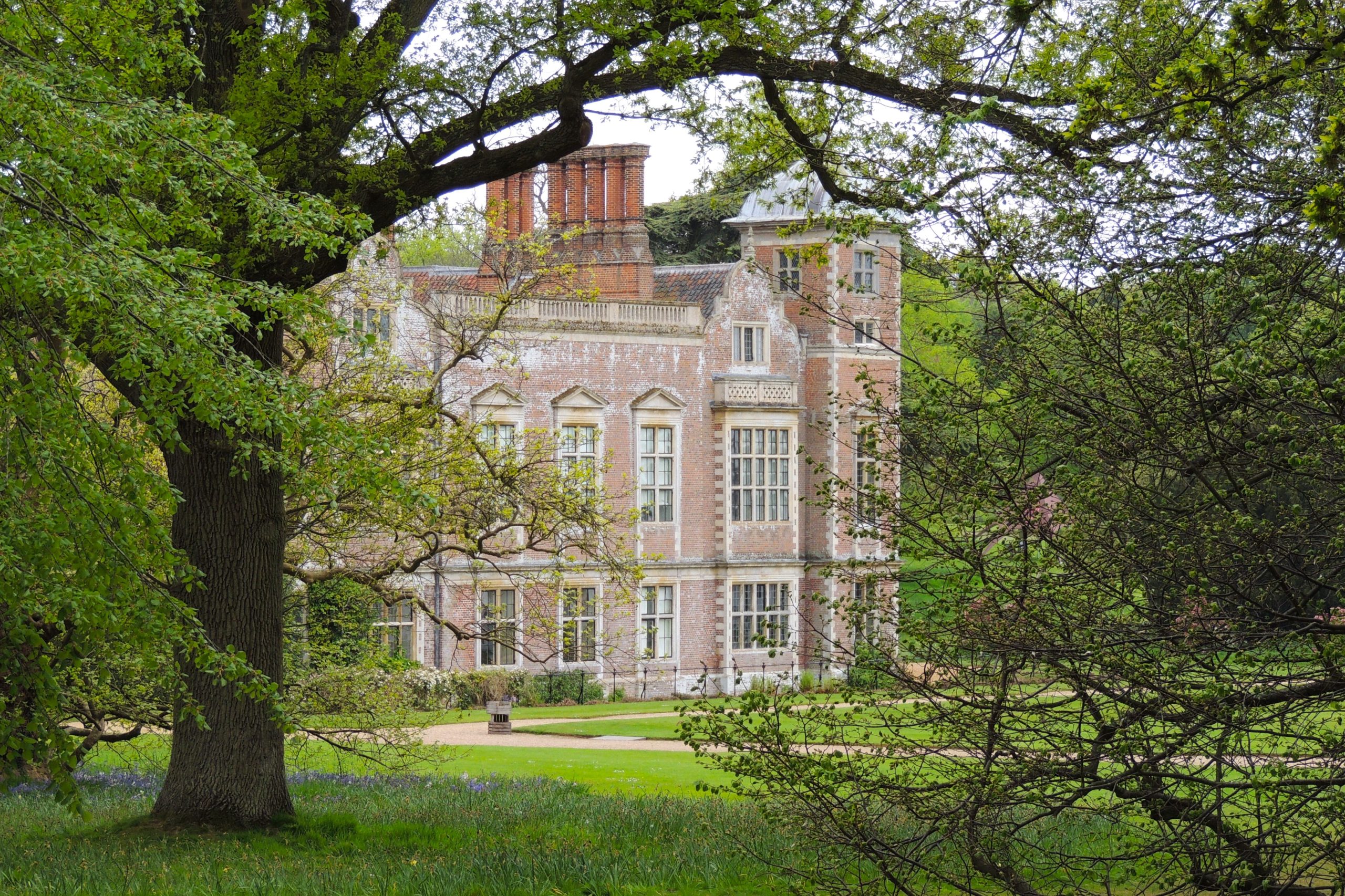 Blickling Hall's facade surrounded by lush greenery in summer.